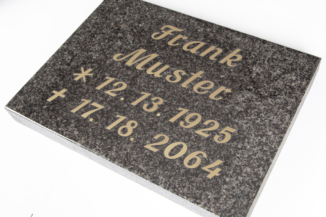Detailreiche Intarsien-Inschrift in Granit – Steinmetz Bartels aus Meisterhand Grabstein mit Intarsien-Inschrift aus grauem Granit, seitlich oben betrachtet